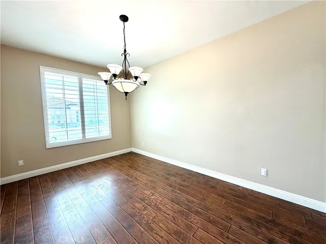 a view of a room with wooden floor chandelier and windows