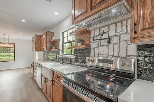 a kitchen with stainless steel appliances granite countertop a sink and a stove