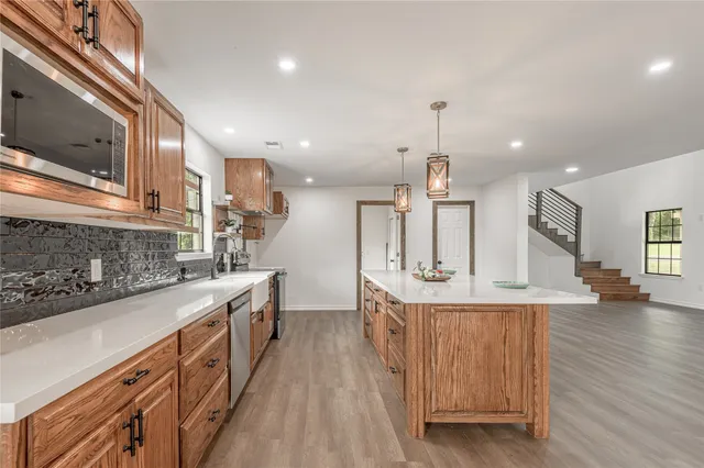 a kitchen with stainless steel appliances kitchen island granite countertop a sink a stove and a wooden floors