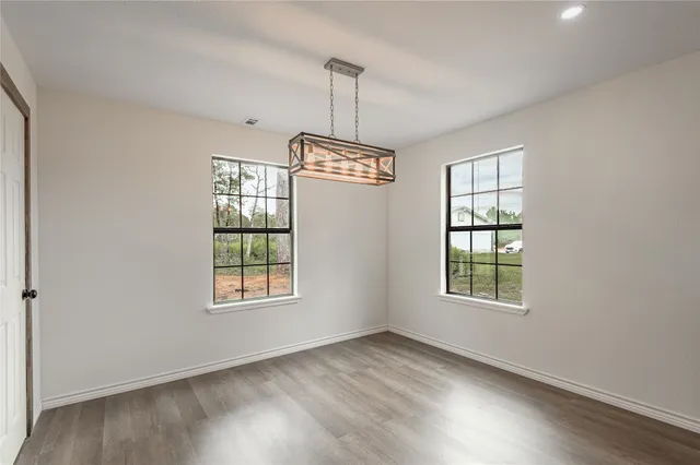 an empty room with wooden floor cabinet and windows