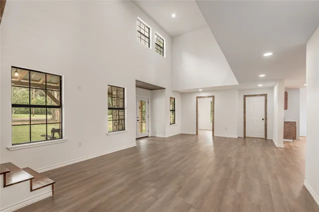 a view of an empty room with window and wooden floor