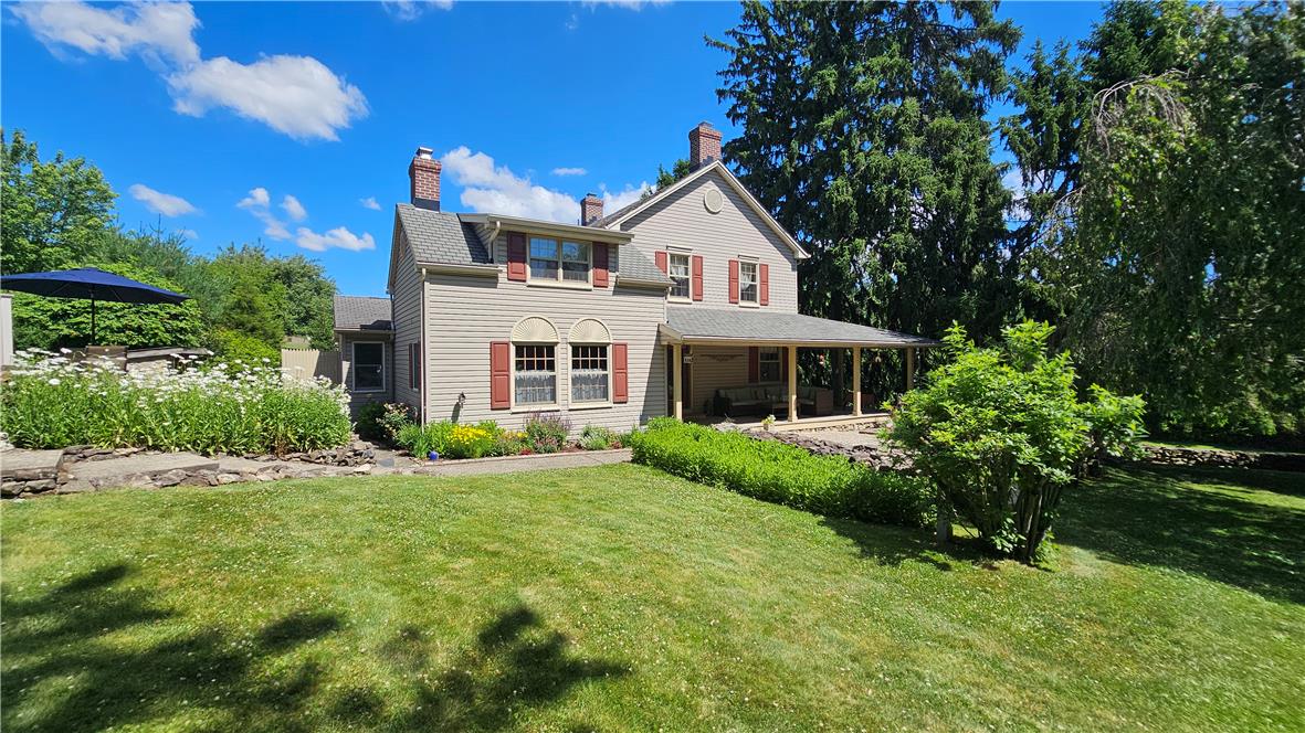 A charming residence with a covered porch offers abundant outdoor space and mature trees.