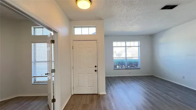 an empty room with wooden floor and windows