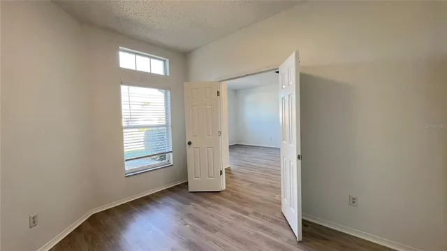 an empty room with wooden floor closet and windows