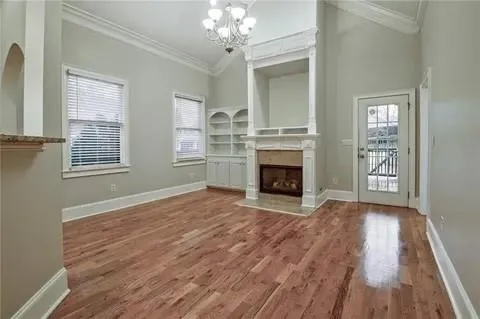 a view of an empty room with wooden floor fireplace and a window