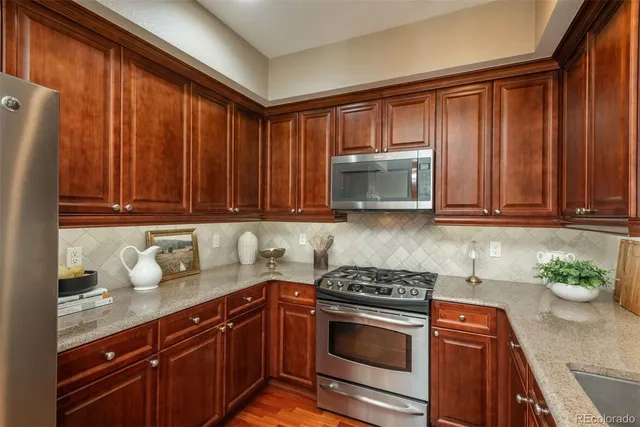 a kitchen with granite countertop stainless steel appliances a stove microwave and refrigerator