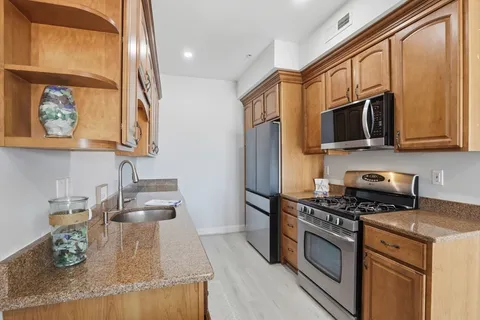 a kitchen with stainless steel appliances granite countertop a stove a sink and a microwave