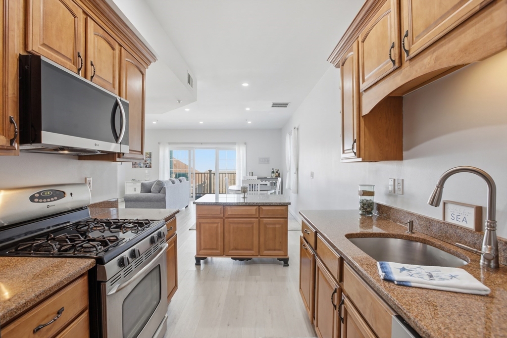 233 Beach Road, Unit A10 Salisbury, MA 01952 - Photo 7 of 39 a kitchen with stainless steel appliances granite countertop a sink stove and refrigerator