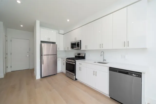 a kitchen with a sink a refrigerator and white cabinets
