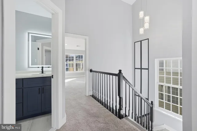 a view of a hallway with wooden floor and a bathroom
