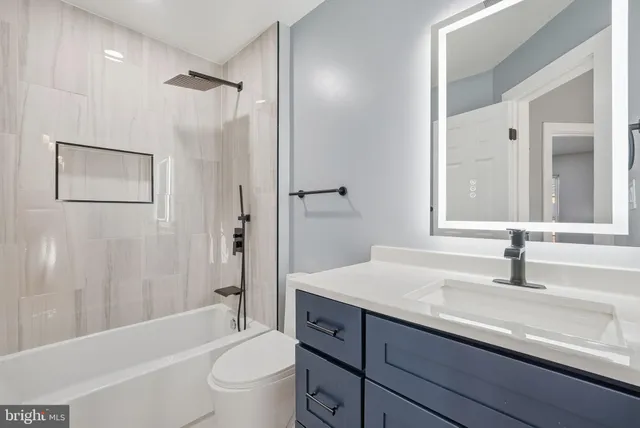 a bathroom with a granite countertop sink a toilet and shower