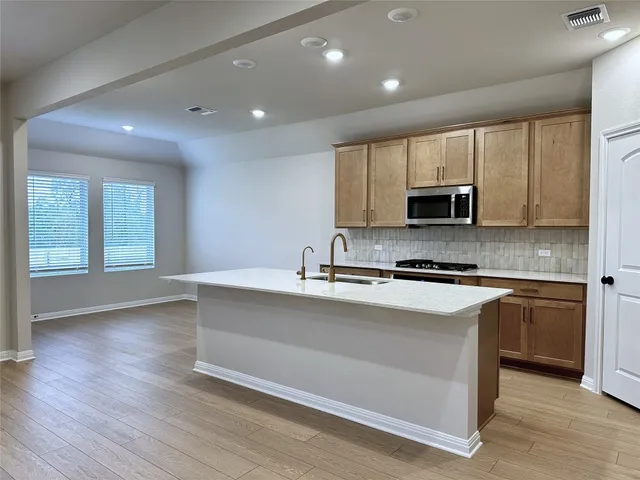 a large kitchen with stainless steel appliances granite countertop a stove a sink and a microwave