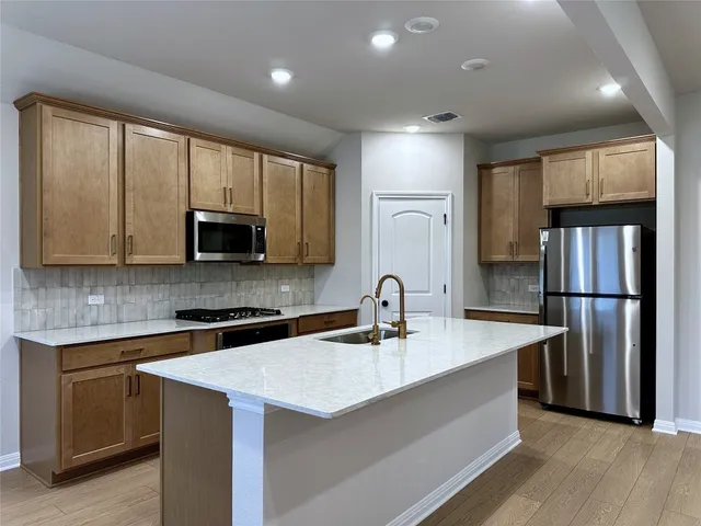 a kitchen with stainless steel appliances granite countertop a sink a microwave a refrigerator and cabinets