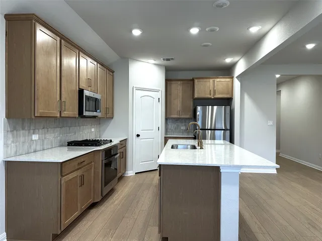 a large kitchen with stainless steel appliances kitchen island granite countertop a stove refrigerator and a sink