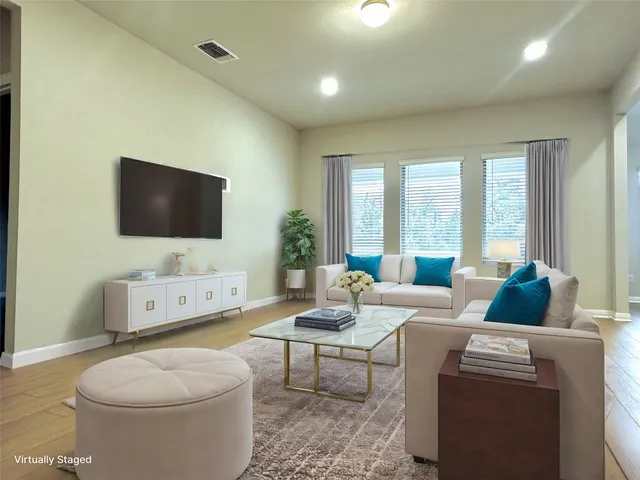 a living room with furniture a flat screen tv and a floor to ceiling window