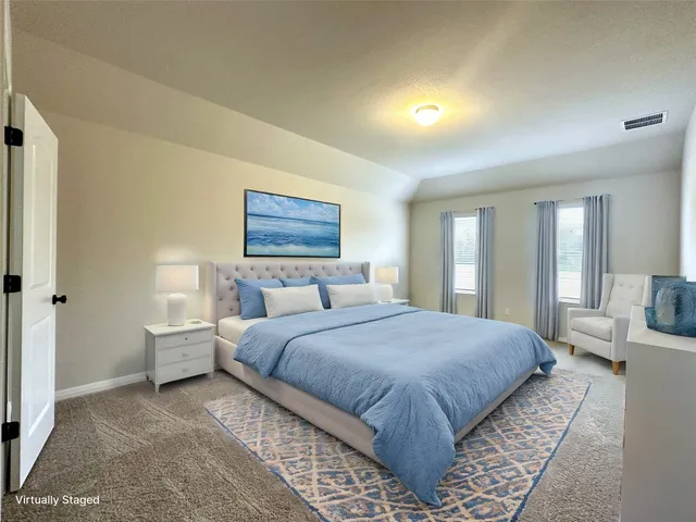 a bedroom with a large bed a rug and painting on the wall