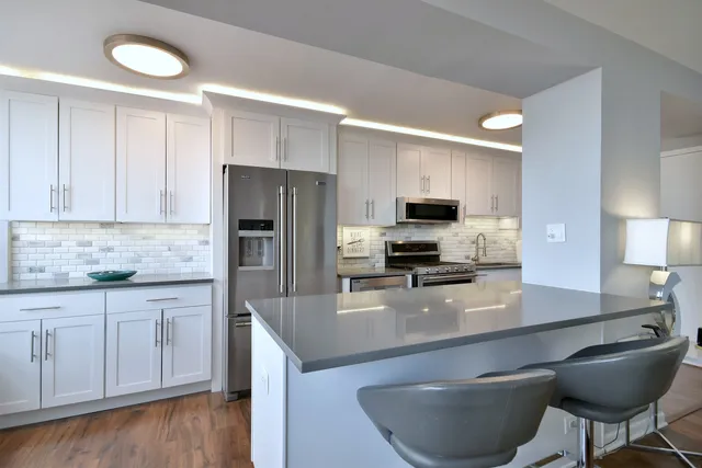 a kitchen with stainless steel appliances a sink a stove a microwave a refrigerator and cabinets