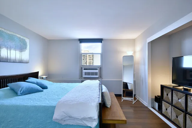 a bedroom with a bed and a flat tv screen on a dresser