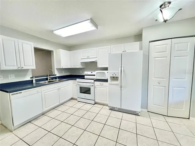 a kitchen with white cabinets a sink and white appliances