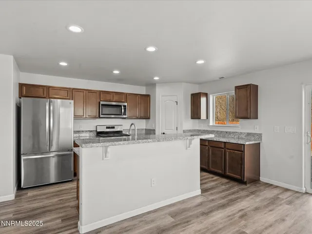 a kitchen with stainless steel appliances granite countertop a refrigerator a stove top oven a sink and dishwasher with wooden floor