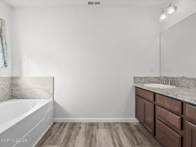 a bathroom with a granite countertop sink and a bathtub