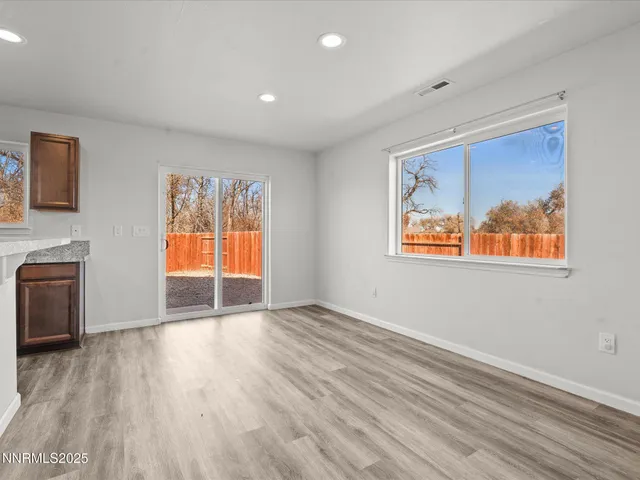 a view of an empty room with a window and wooden floor