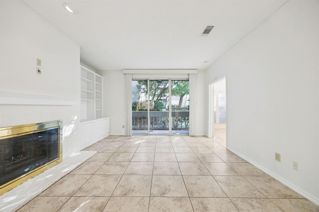 5310 Keller Springs Road, Unit 612 Dallas, TX 75248 - Photo 11 of 33 Fireplace in the spacious living area and built-in bookshelves open to a covered patio.