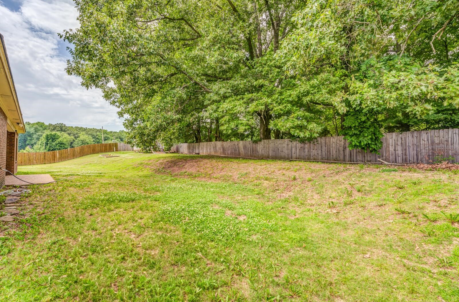 4671 Hampton Ridge Lane Bartlett, TN 38002 - Photo 40 of 40 Expansive backyard featuring a partial brick exterior, concrete patio, wood privacy fencing, and mature trees providing natural screening