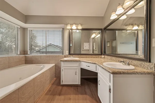 a bathroom with a granite countertop tub sink and mirror