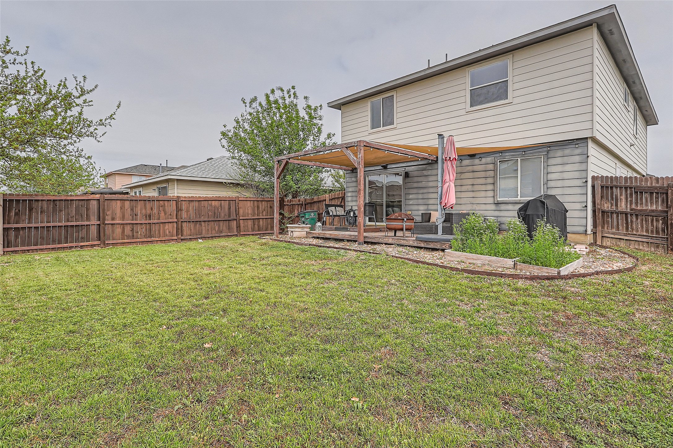 18021 Prairie Verbena Lane Elgin, TX 78621 - Photo 26 of 33 A spacious backyard with a private fence, featuring a covered patio for outdoor enjoyment.