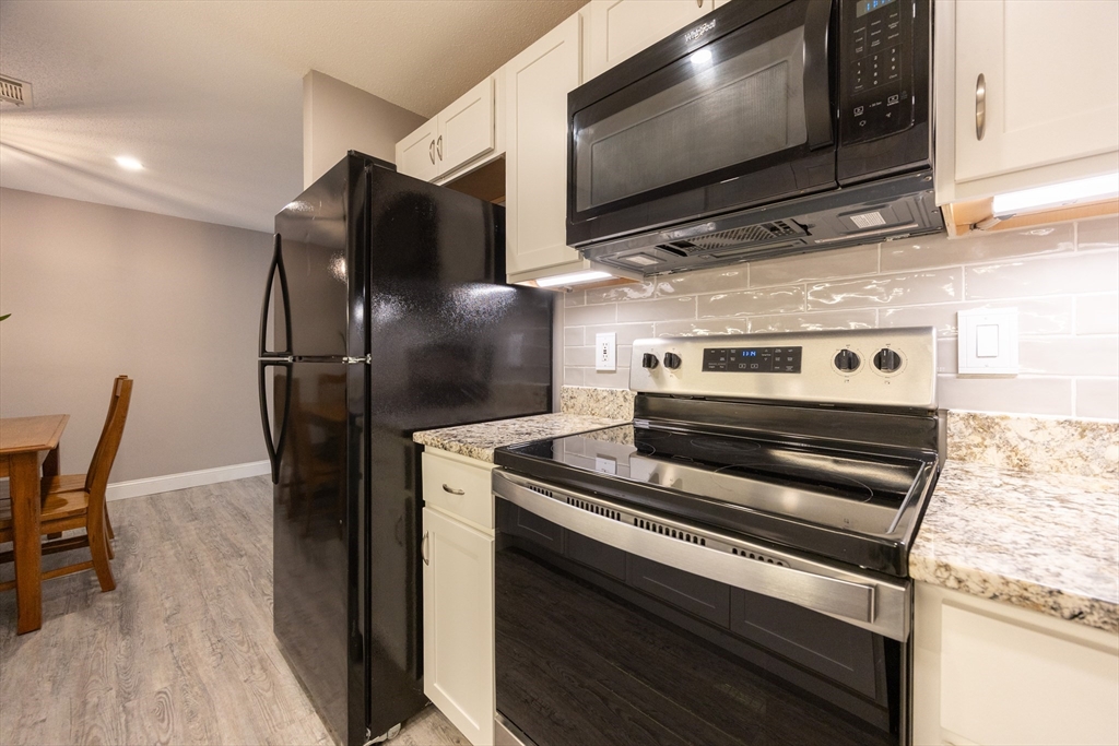 605 Franklin Crossing Road, Unit 605 Franklin, MA 02038 - Photo 8 of 31 a kitchen with stainless steel appliances and wooden floor