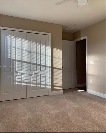 an empty room with chandelier fan and windows