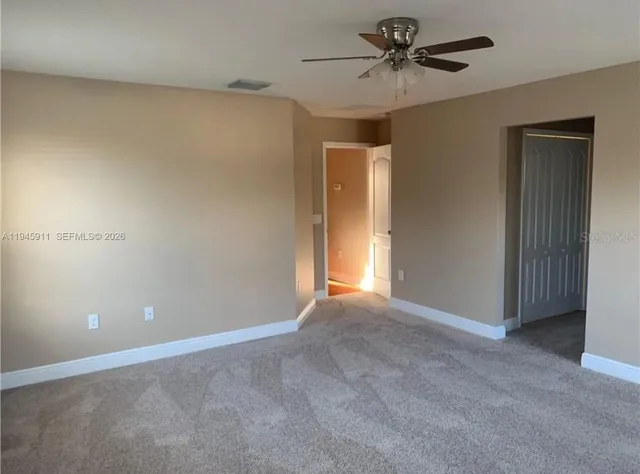 a view of an empty room with a chandelier fan