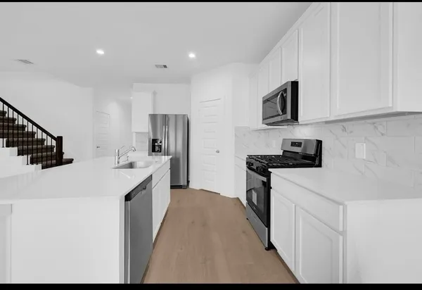 a kitchen with stainless steel appliances granite countertop a sink stove and refrigerator