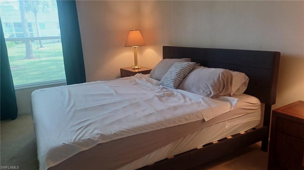 716 Landover Circle, Unit 102 Naples, FL 34104 - Photo 12 of 31 a bed sitting in a bedroom next to a window