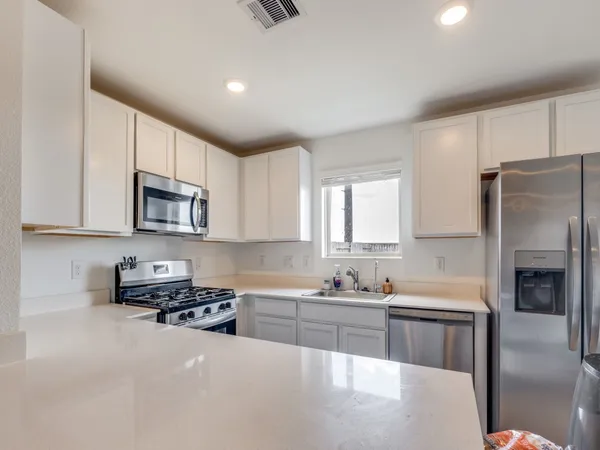 a kitchen with stainless steel appliances granite countertop a refrigerator a stove and a sink