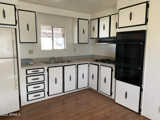 a kitchen with granite countertop a refrigerator a sink and white cabinets