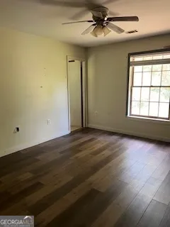 an empty room with wooden floor fan and windows