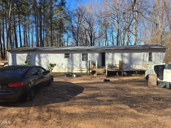 a view of a back yard of the house with cars parked