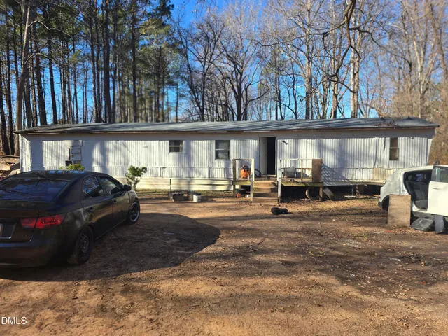 a view of a back yard of the house with cars parked