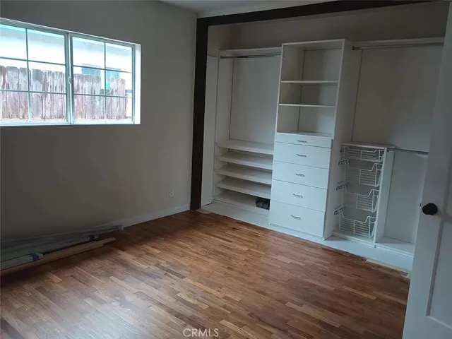 a view of an empty room with wooden floor and windows