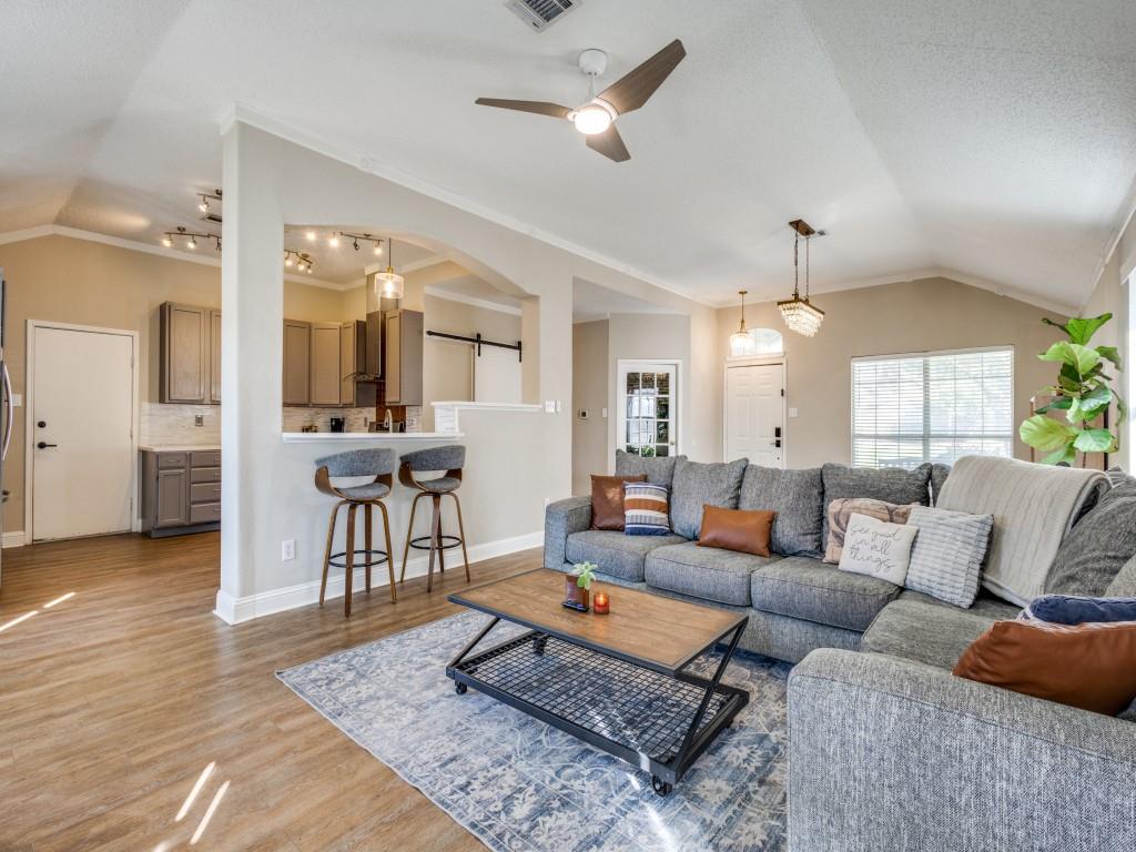 7129 Sample Drive The Colony, TX 75056 - Photo 11 of 25 Living area with vaulted ceiling, ceiling fan, wood finished floors, a barn door, and ornamental molding