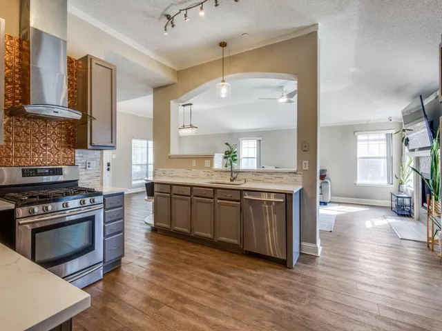 a kitchen with stainless steel appliances granite countertop a stove a sink dishwasher and a refrigerator with wooden floor