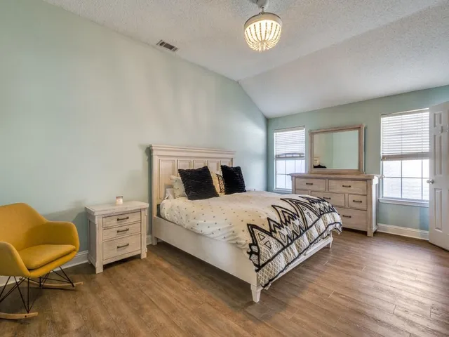 a bedroom with a bed and a chair with the wooden floor