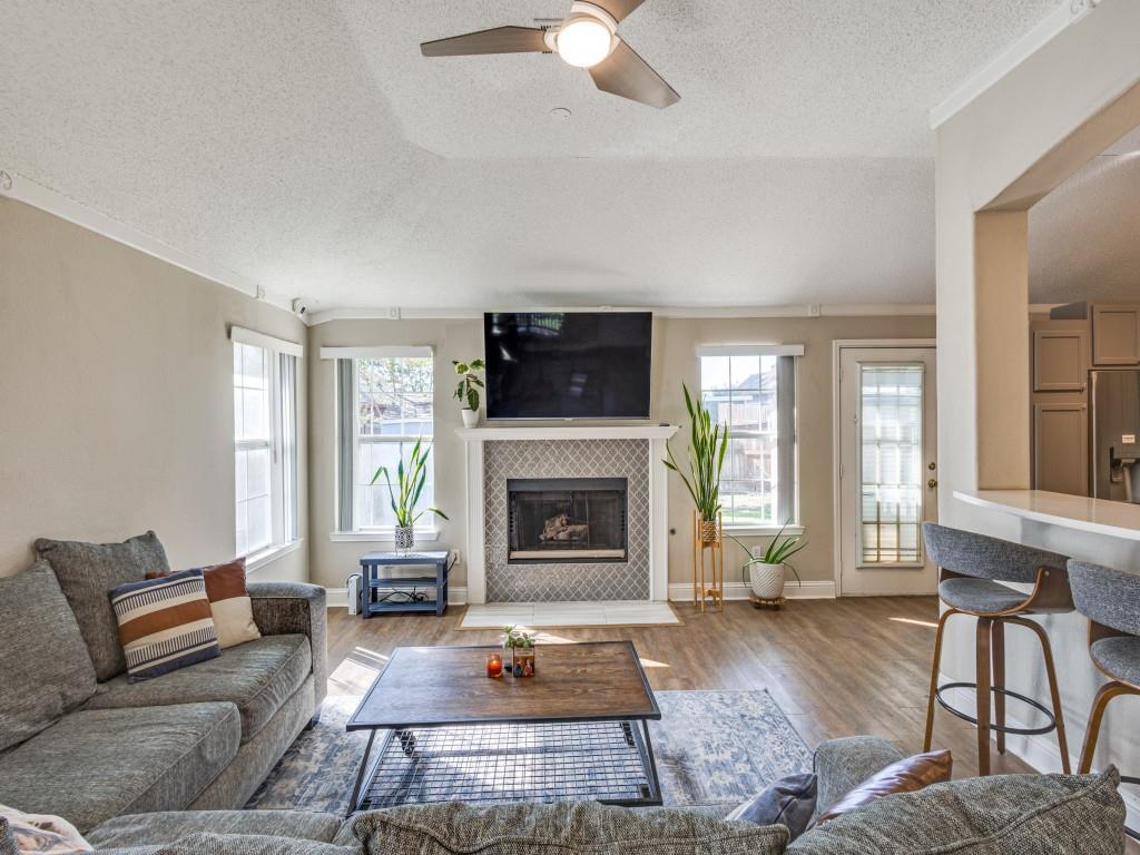 7129 Sample Drive The Colony, TX 75056 - Photo 5 of 25 Living area with wood finished floors, plenty of natural light, a textured ceiling, ornamental molding, and a tiled fireplace