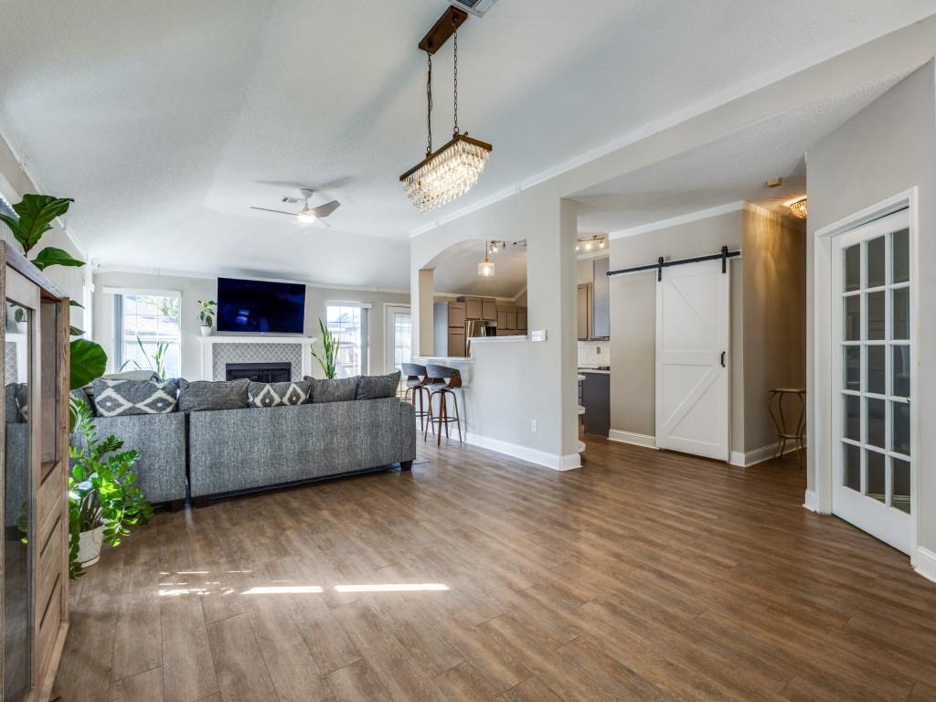 7129 Sample Drive The Colony, TX 75056 - Photo 6 of 25 Living room featuring a barn door, crown molding, a fireplace, dark wood finished floors, and a ceiling fan