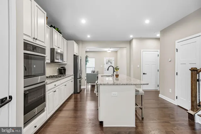 a large kitchen with stainless steel appliances granite countertop a lot of counter space and wooden floor