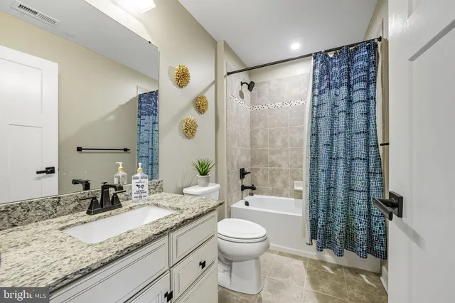 a bathroom with a granite countertop sink a toilet and shower
