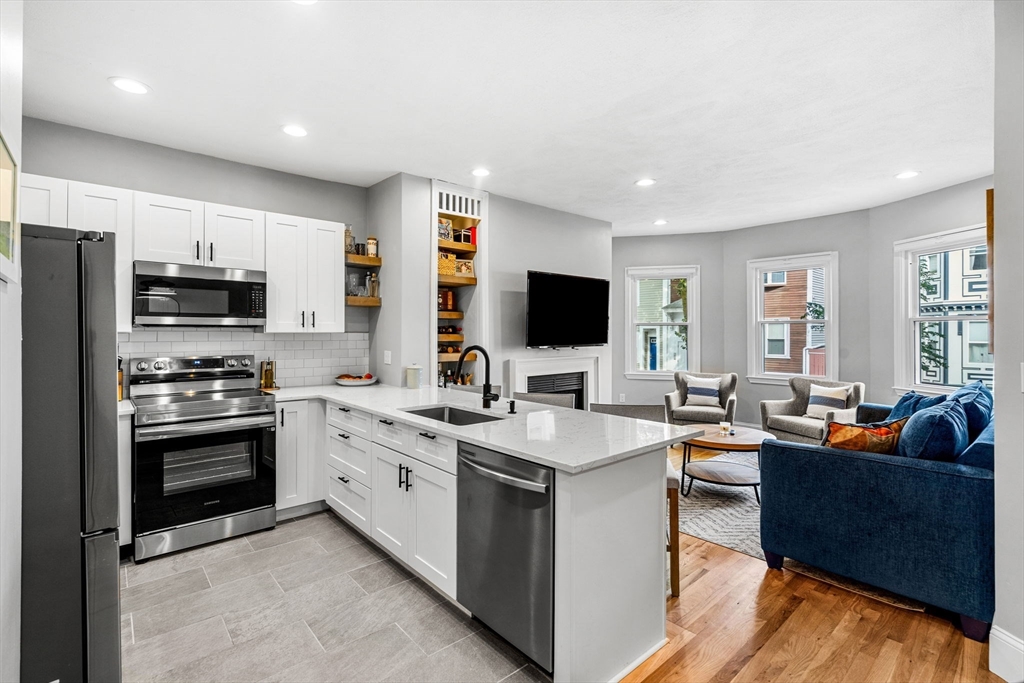 7 O Street, Unit 1 Boston, MA 02127 - Photo 5 of 15 a large kitchen with stainless steel appliances a stove a sink dishwasher a microwave oven with a dining table and chairs