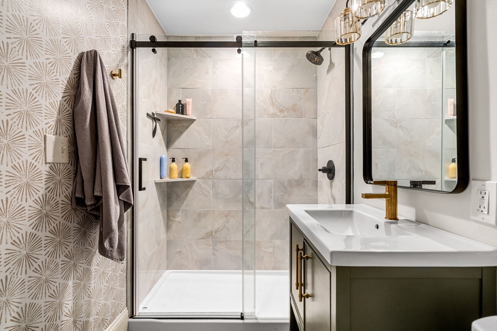 7 O Street, Unit 1 Boston, MA 02127 - Photo 9 of 15 a bathroom with a granite countertop shower a sink and a mirror